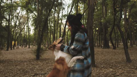 A woman pets her dog in the park