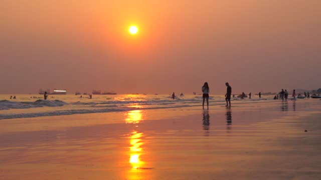 People laugh and play again in the sea at sunset