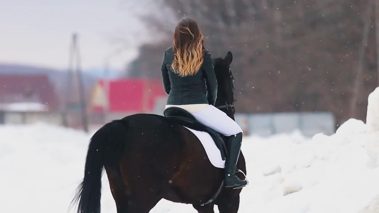 A young woman with long hair riding a horse in a village in winter time