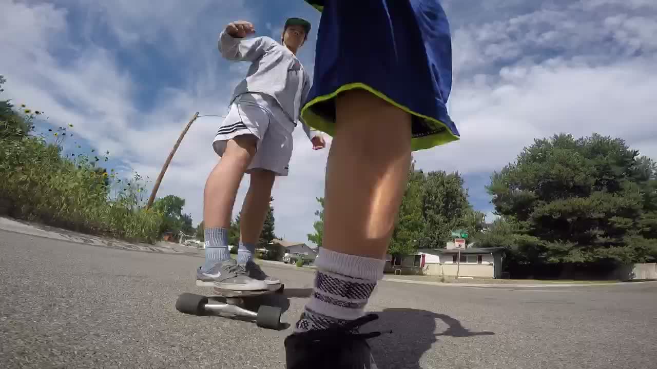 Guy on scooter kicking to speed up kicks friend on skateboard off