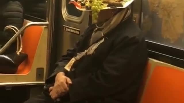 Man wears crazy straw fruit hat on subway