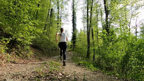 A Woman Running Uphill In The Forest Trail