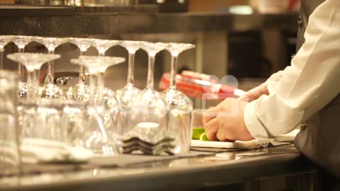 Bartender cutting lemon for making the drink