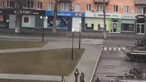 A resident of Kherson waving Ukrainian flags in front of Russian infantry