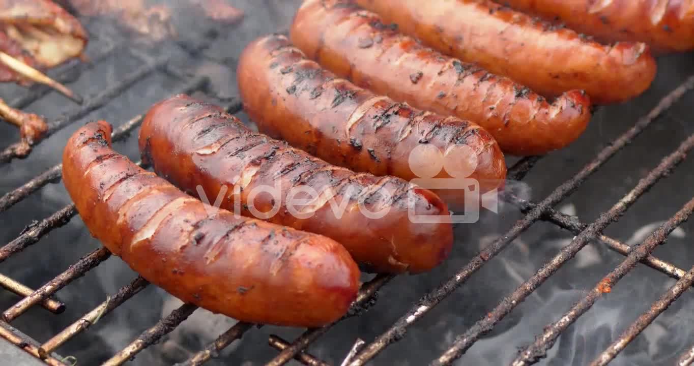 Hot tasty grilled sausages frying on smoking barbecue Slow motion video