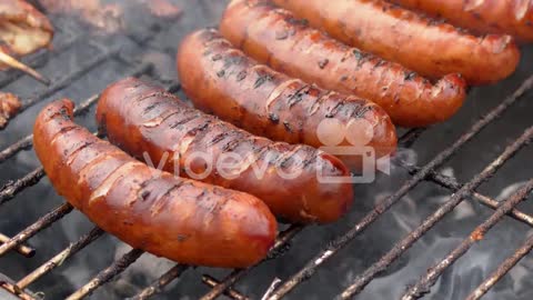 Hot tasty grilled sausages frying on smoking barbecue Slow motion video