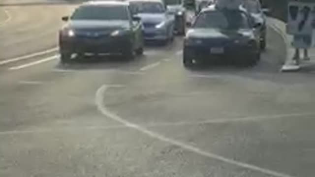 Small black car in traffic with white surf board