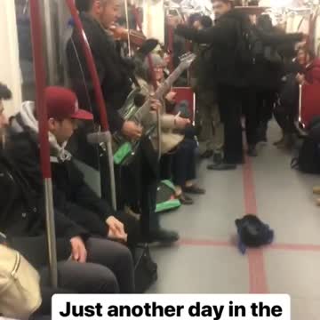 Two guys play electric guitar and violin on subway train
