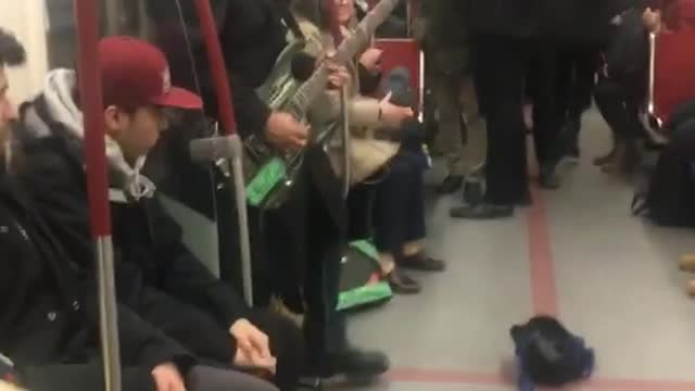 Two guys play electric guitar and violin on subway train