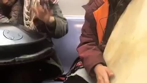 Two guys playing odd instruments on train