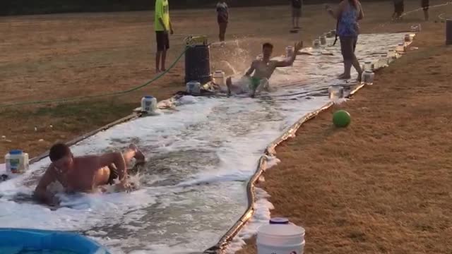 Guy green shorts slips on diy slip and slide outside hits head