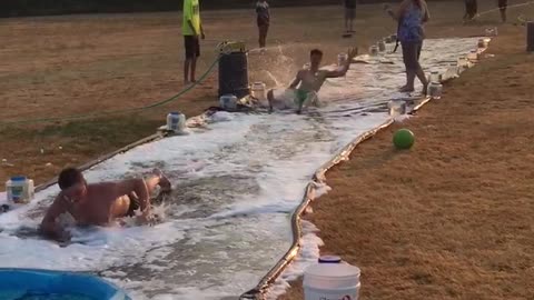 Guy green shorts slips on diy slip and slide outside hits head
