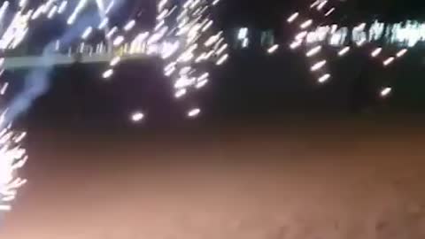 Several men are playing with firecrackers on the beach.