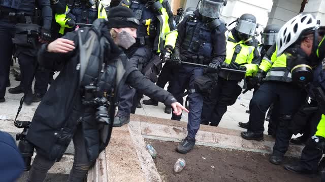 Capitol officer hands protester her dropped phone back after heavy scuffle