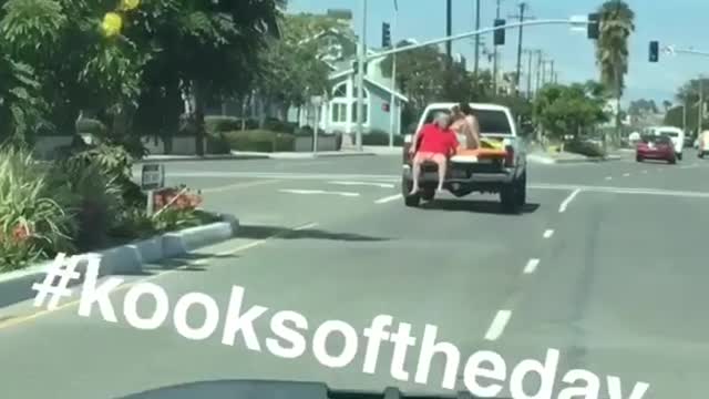 Red shirt guy riding on open trunk of truck