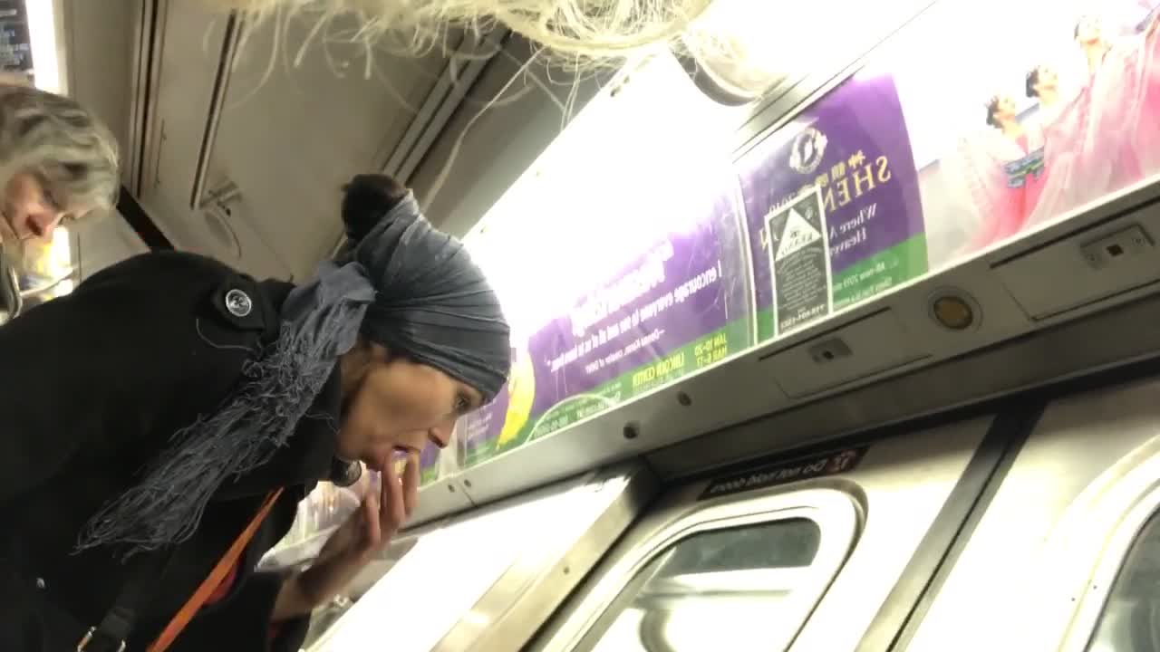 Woman on a subway train fingers her mouth