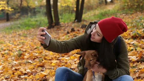 Smiling woman with dog taking selfie in autumn