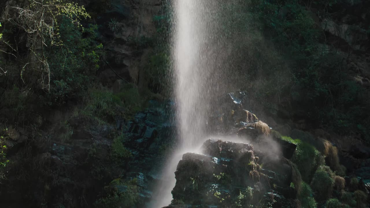 A lush waterfall falls into a rock with moss