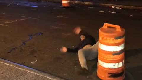 Guy kicks yellow cone and ends up falling on his back