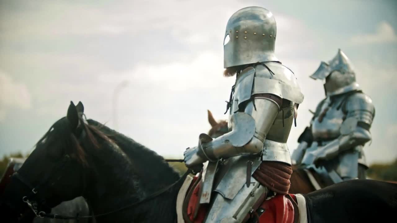 A man knight in the armor riding a horse - another knight comes next to him