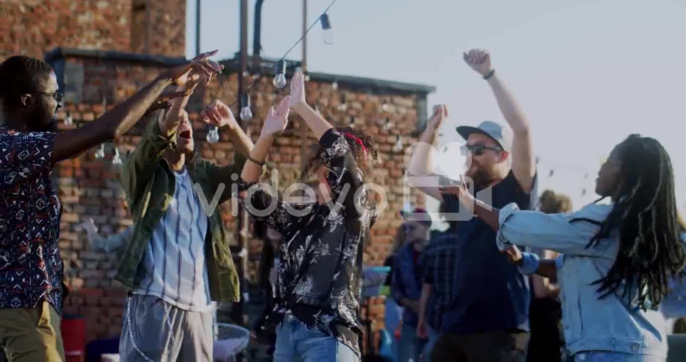 Young Stylish Woman And Happy Group Of People Dancing And Gaving Fun On The Rooftop