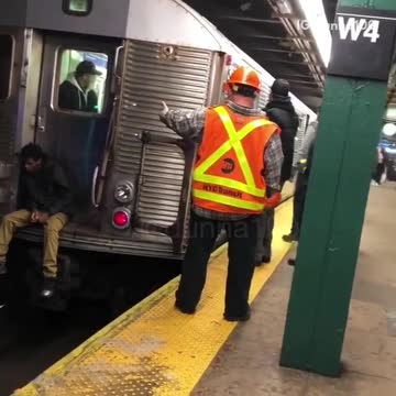 Sad guy sits on the edge of subway train and waits for train to go, attendants tell him to get off