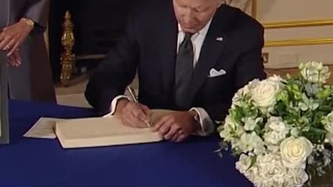 Biden takes out notes from his pocket to write & Sign in Book of Condolences
