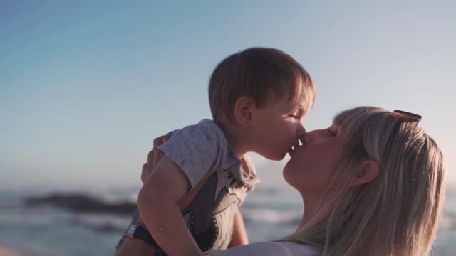 A Mother Kissing Her Toddler Son While Carrying Him On Her Arms