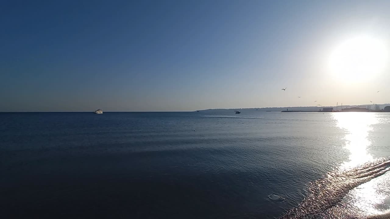 A beautiful natural view of the sunset, the presence of birds and calm waves