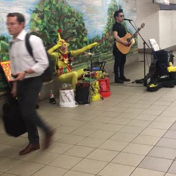Man singing another man in yellow plays drums