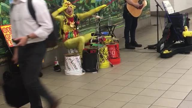 Man singing another man in yellow plays drums