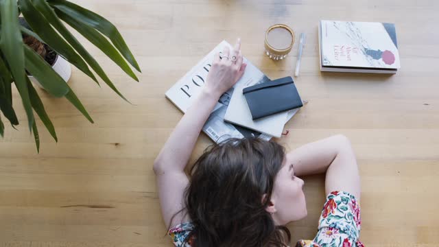 High Angle Shot Woman Lying on Wooden Table then Getting a Book to Read