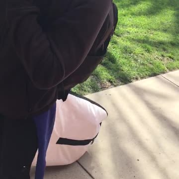 Guy carries surfboard in a giant bag