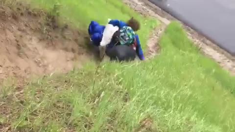 Guy in blue jacket runs down a hill with his belongings and falls down