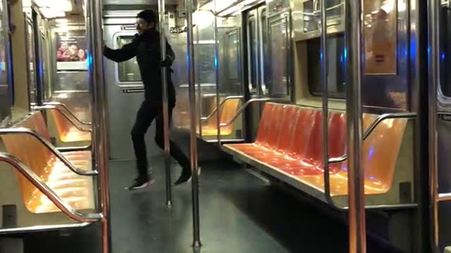 Man in black hoodie runs through empty subway train