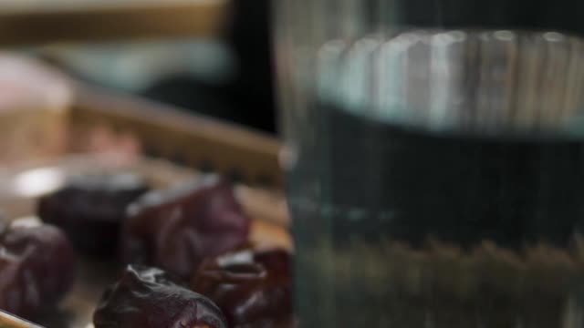 a-woman-holding-a-tray-with-dates-and-glass-of-water