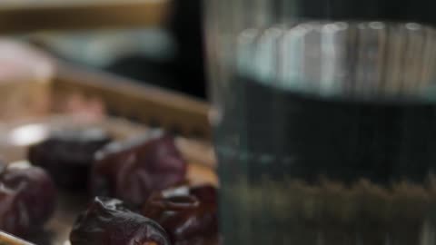 a-woman-holding-a-tray-with-dates-and-glass-of-water