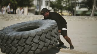 Bulk Guy Lift Big Car Tire On Beach