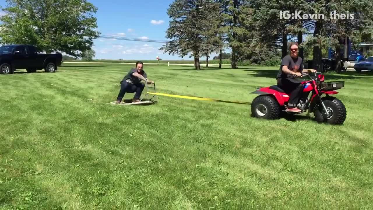 Three wheeler pulls a man on a folding table who then falls off