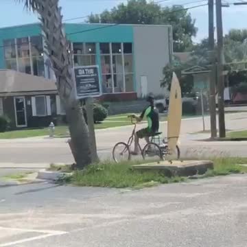 Guy riding bike with yellow board on back
