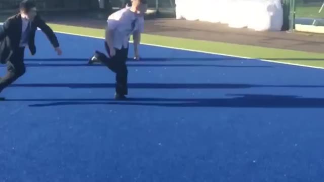 White shirt kid slides into kid in suit's legs on blue turf field