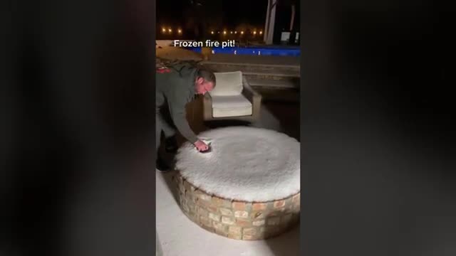 Guy Lights Frozen Fire Pit At the Back Porch Of His House