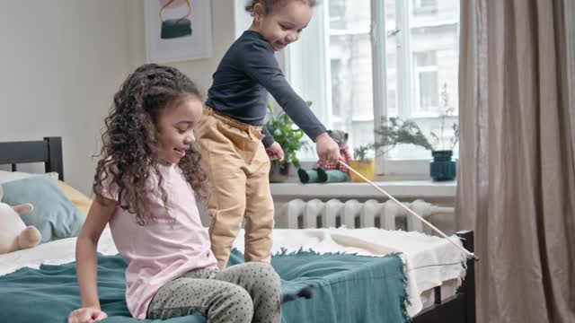 Kids Playing Catch The Bait With Their Cat In Their Bedroom