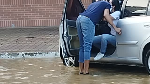 Man Carries Woman to Car in Flooded Street