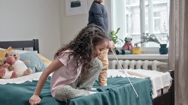 Kids Playing Catch The Bait With Their Cat In The Bedroom