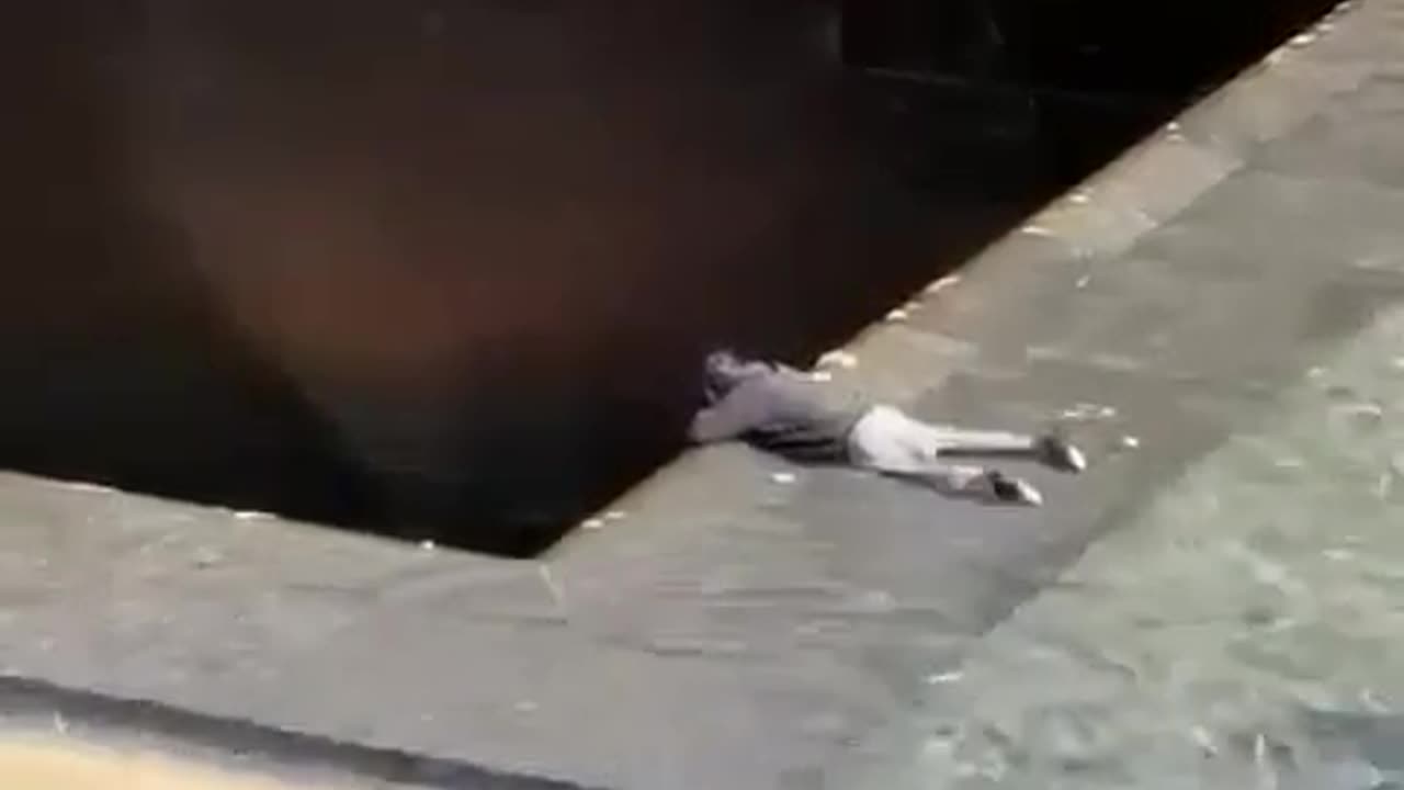 A man at the 9/11 memorial drops down to where the water flows.