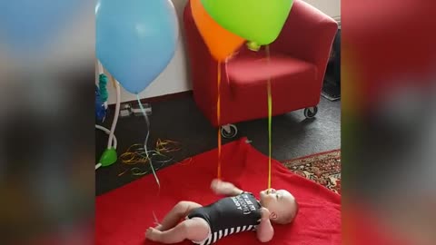 Baby Laughs A Balloons Tied To Hands And Feet