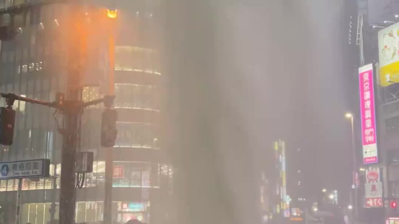 Water shoots out of a manhole near Shinjuku station after heavy rain hit Tokyo, Japan