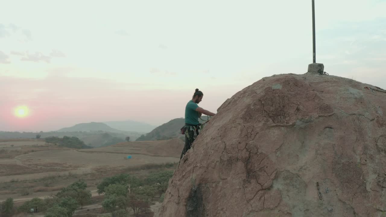 Man climbing to the top of a large rock