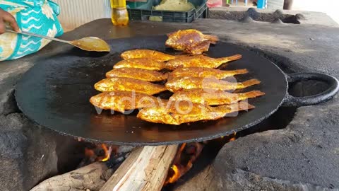 Spicy fishes being fried in big cast iron pan in road side eatery Hogenakkal Tamil Nadu India